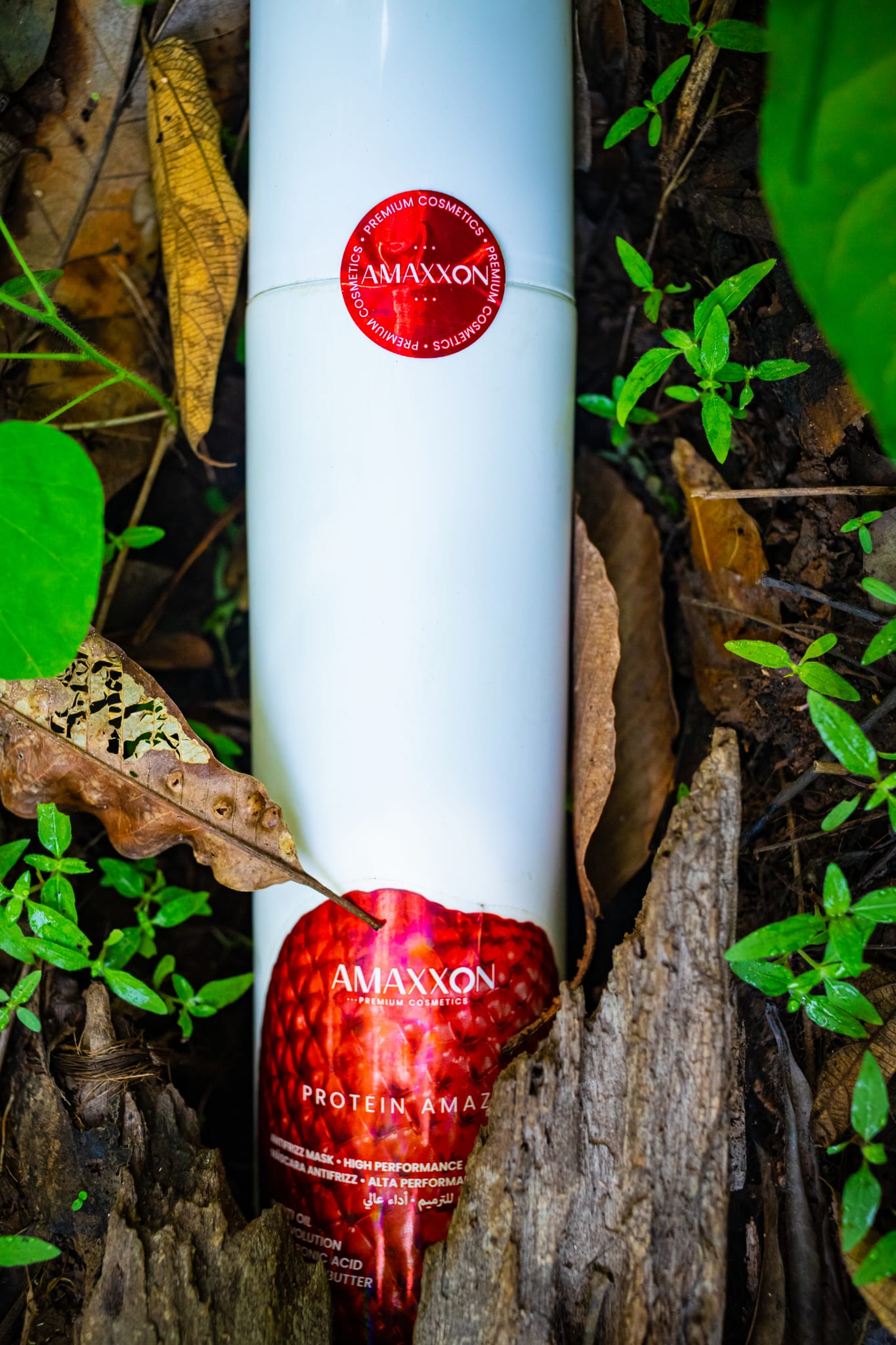 Flacon Protein Amazon d'Amaxxon posé sur le sol d'une forêt amazonienne, parmi les feuilles et les jeunes pousses